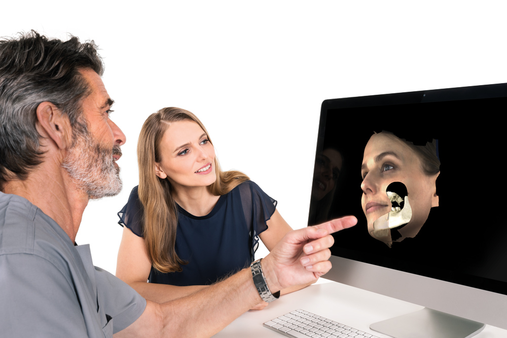 Dental nurse explaining software results on computer screen to woman patient